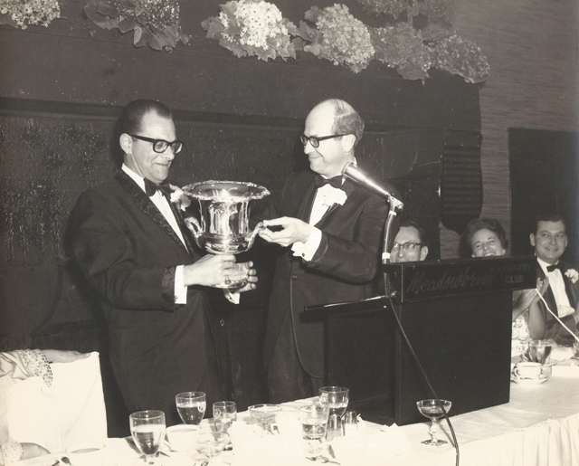 Norman Miller (L) receives a trophy from Dr. Alan Wasserman to mark the completion of Miller's second term as the country club's president at the Meadowbrook President's Ball, 1966.