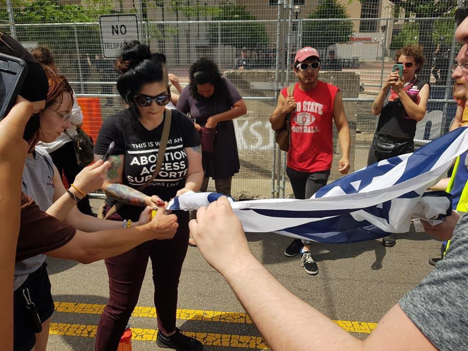 Counterprotesters attempt to set an Israeli flag on fire near the Klan rally at Dayton's Courthouse Square, May 25, 2019. Facebook.