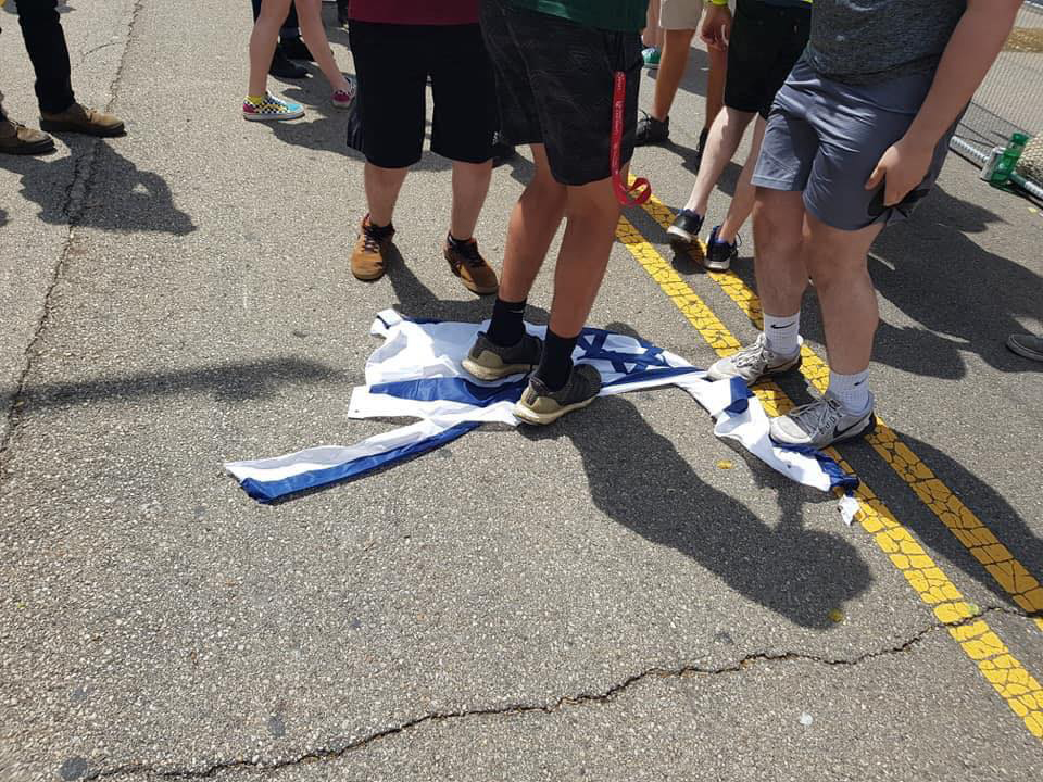 After failing to ignite an Israeli flag, tearing it instead, counterprotesters step on it near the Klan rally at Dayton's Courthouse Square, May 25, 2019. Facebook. 