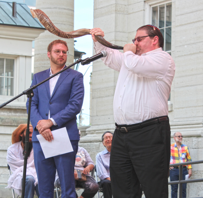 At Dayton's Courthouse Square the day after the Klan rally, Beth Abraham Synagogue's Rabbi Josh Ginsberg sounds the shofar 'to wake us from our moral slumber' as Temple Beth Or's Rabbi Ari Ballaban, director of Dayton's Jewish Community Relations Council looks on. The two participate in NAACP's ritual cleansing of the square, May 26, 2019. Marshall Weiss.